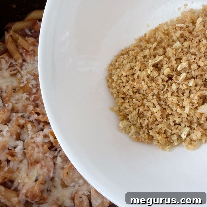 Topping the pasta with panko and fresh basil before serving.