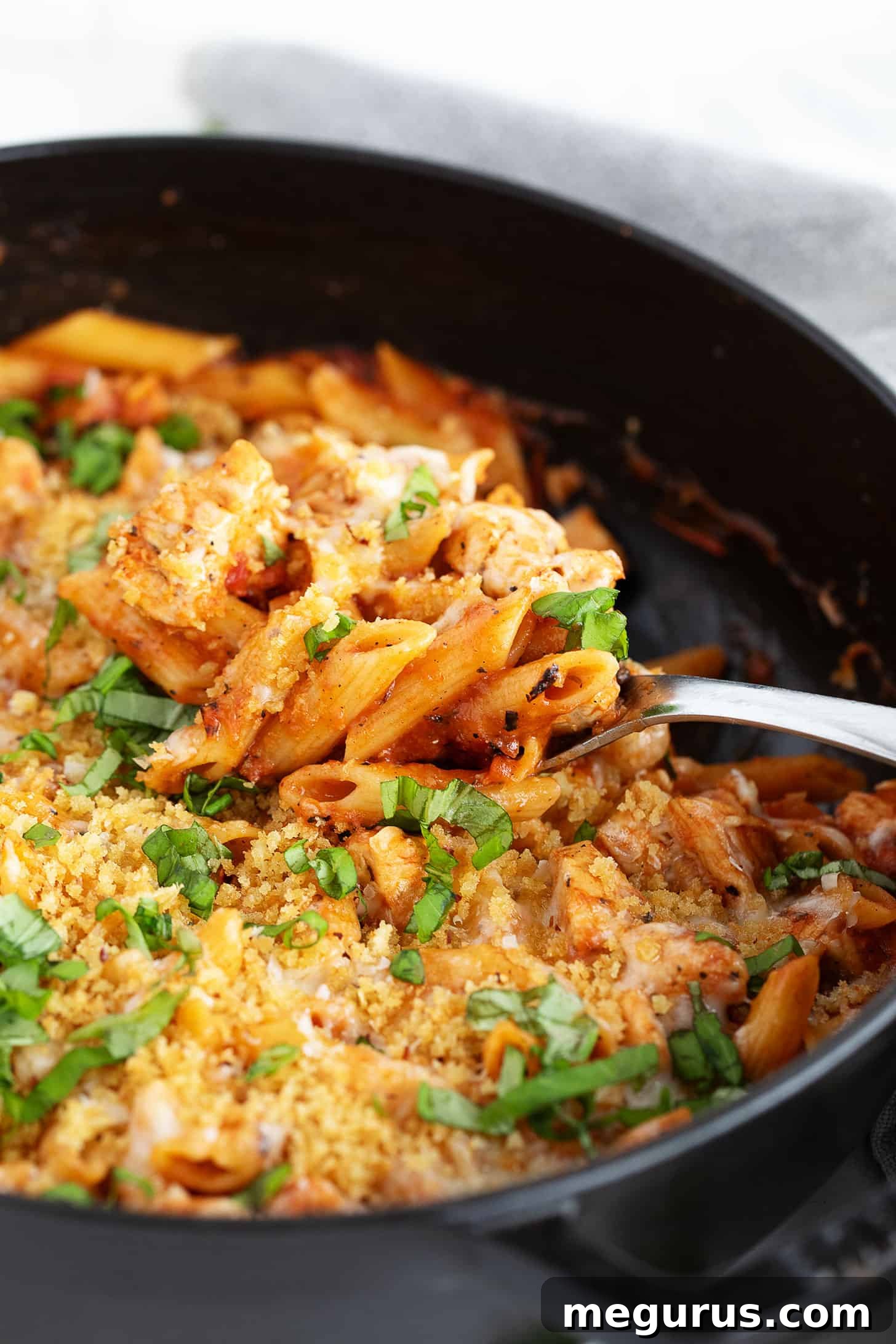 Chicken Parmesan pasta in the skillet, garnished with fresh basil.