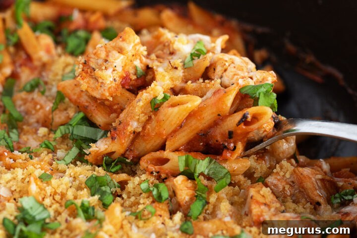 Chicken parmesan pasta in a skillet with a spoon, ready to be served.