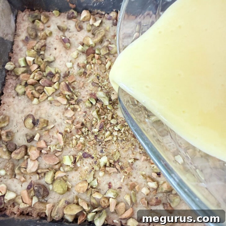 Pouring the lemon filling over the pistachios on top of the base.