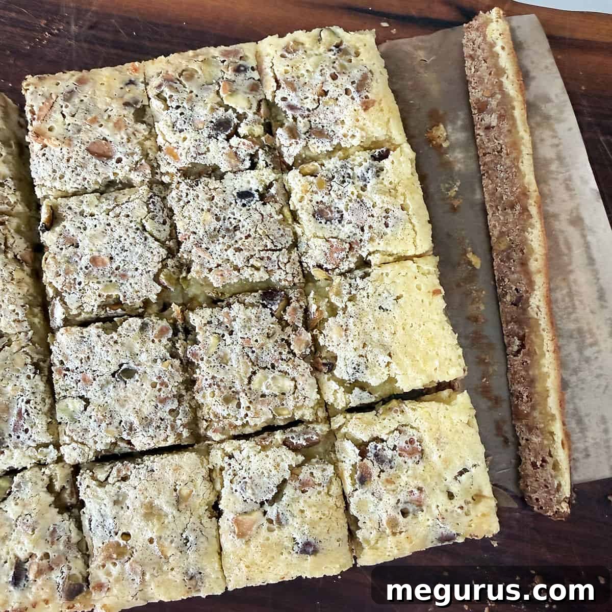 A sharp knife slicing through perfectly chilled lemon pistachio squares, ready for serving.