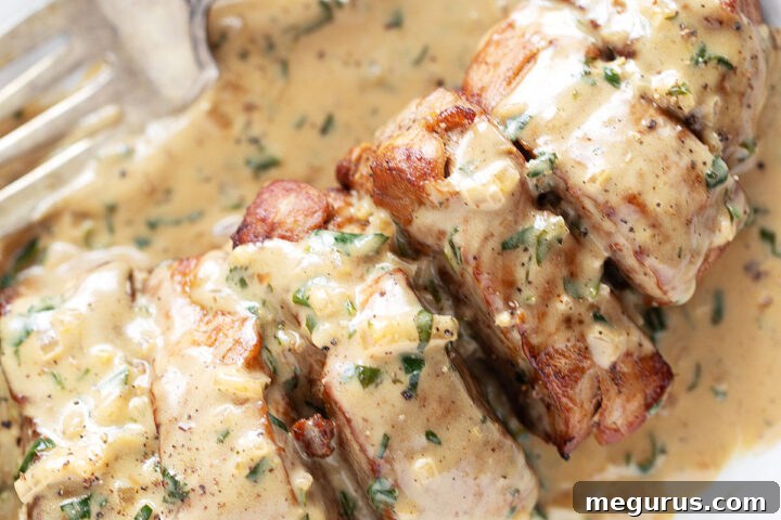 Pork tenderloin medallions on a plate with Dijon sauce.