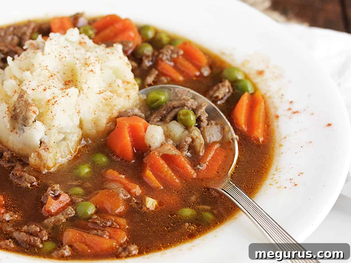 Hearty shepherd's pie soup served in a white bowl, topped with creamy mashed potatoes and a sprinkle of paprika.