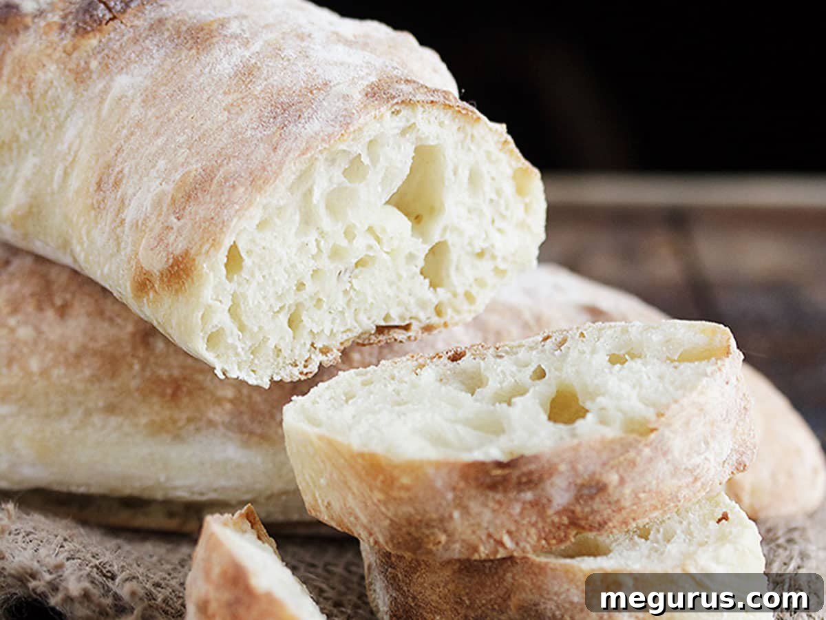 Freshly sliced homemade ciabatta bread on a cutting board, revealing its signature open crumb