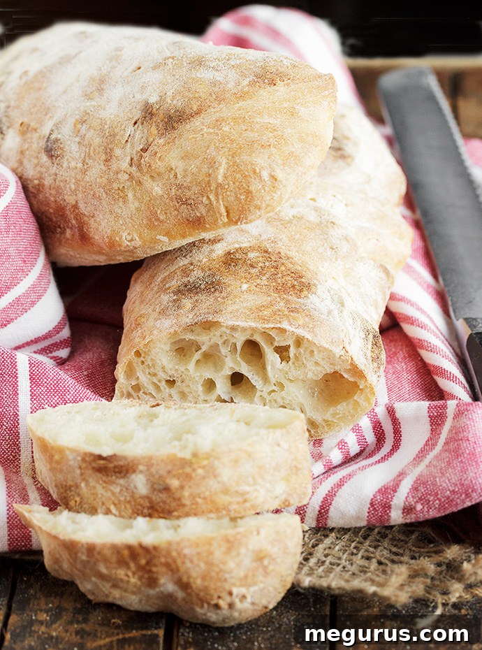 Three loaves of freshly baked homemade ciabatta bread resting on a cooling rack