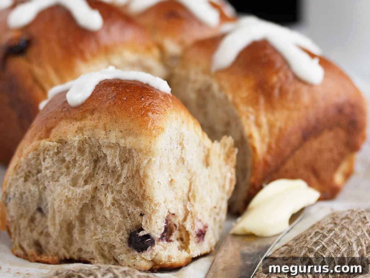 Freshly baked small-batch blueberry lemon hot cross buns with a butter knife and softened butter, ready to be served for Easter breakfast or brunch.
