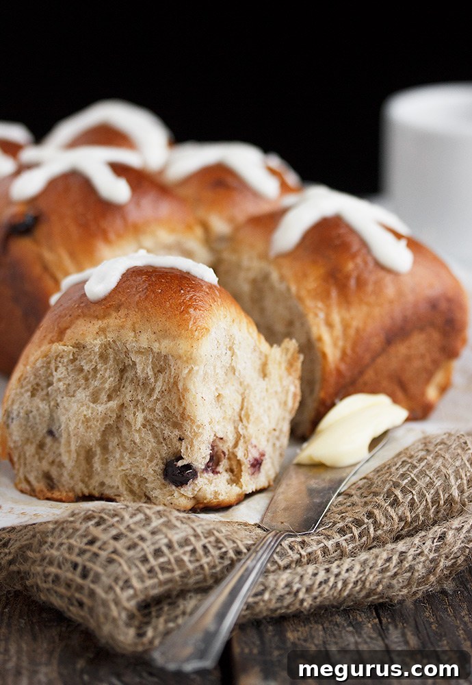 Close-up of a batch of perfectly baked blueberry lemon hot cross buns, showcasing the golden-brown crust and optional white icing crosses.