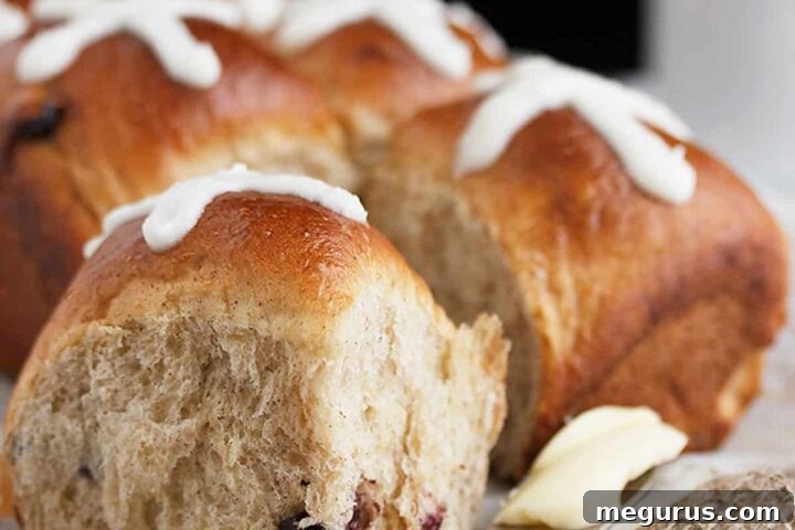 Freshly baked blueberry lemon hot cross buns with a knife and butter