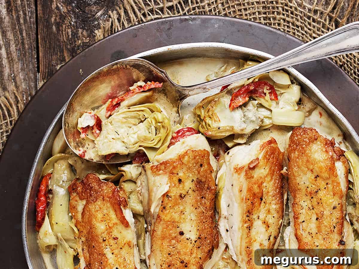 chicken with artichokes and sun dried tomatoes in pan with spoo