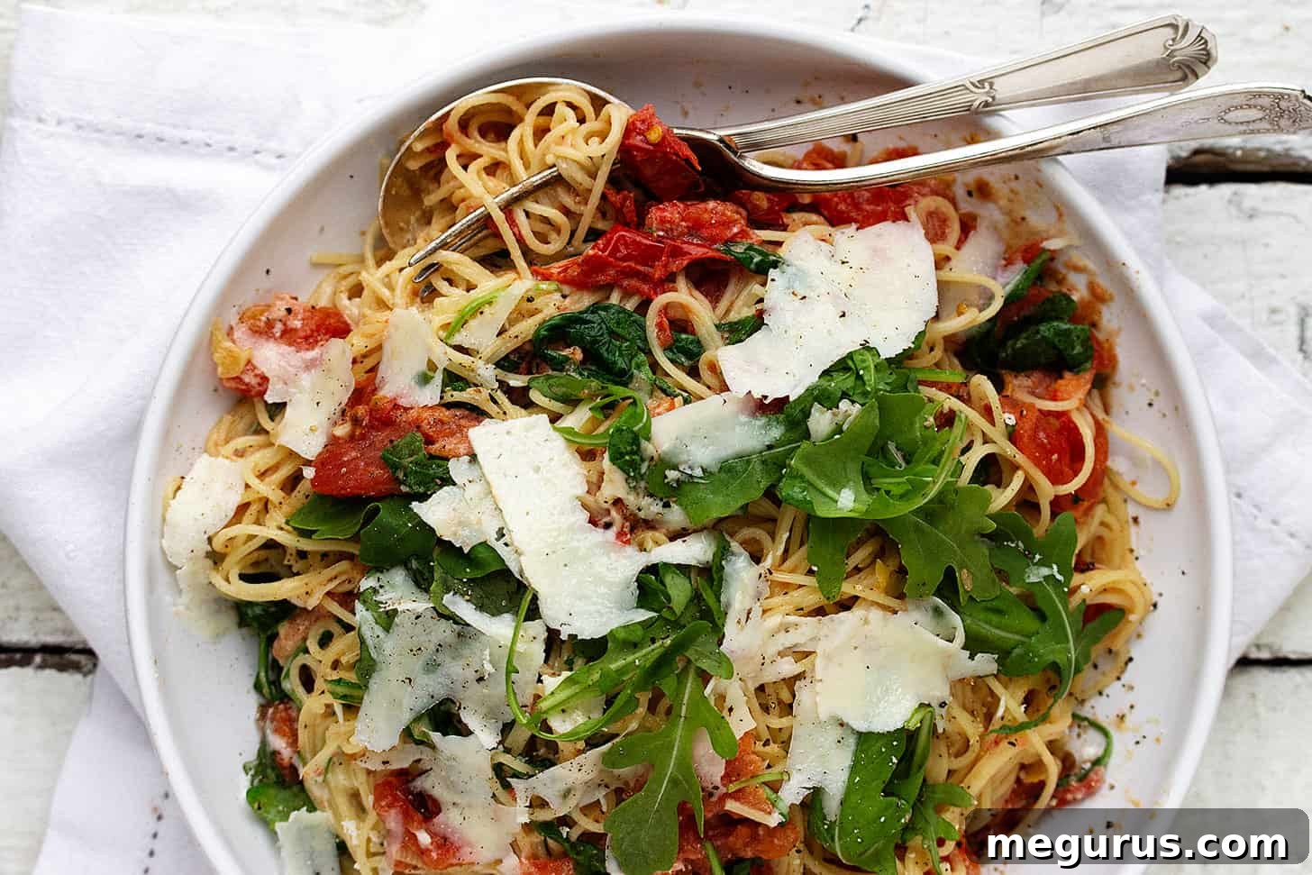 Blistered tomato pasta in a bowl with forks, showcasing vibrant colors and creamy texture