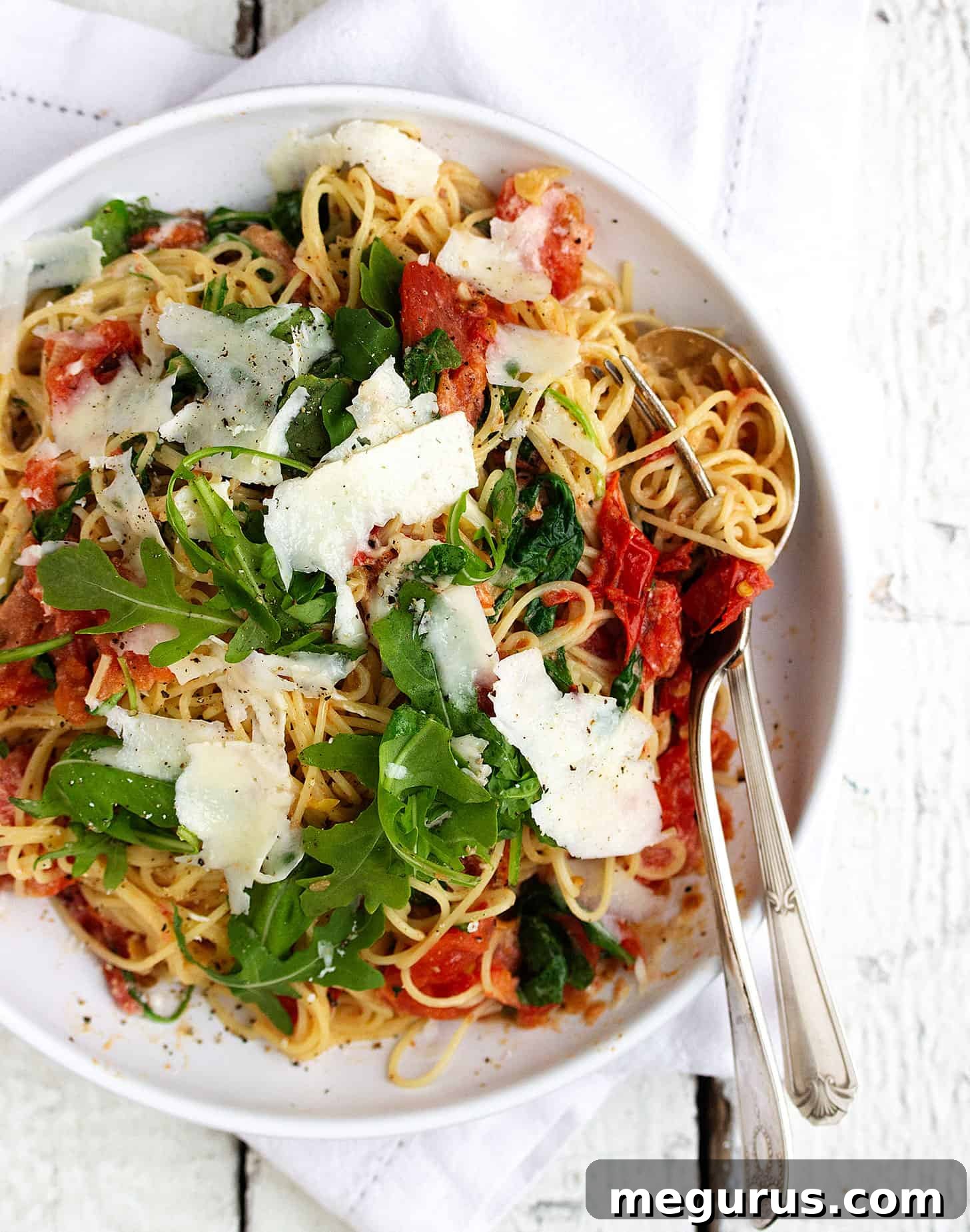 Close-up of blistered tomato pasta in a bowl with a fork, showing texture and ingredients