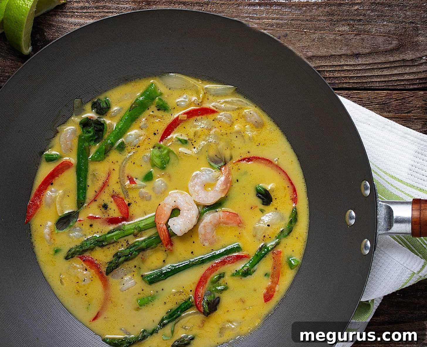 Vibrant Thai green curry shrimp with asparagus simmering in a wok