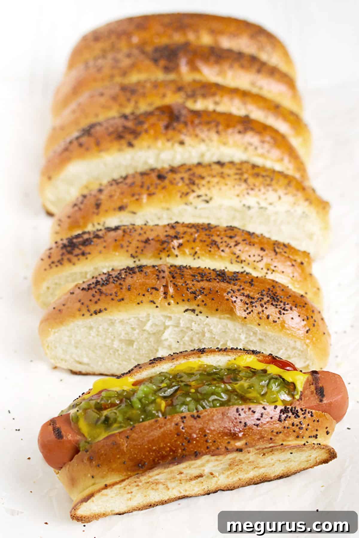 Freshly baked top-sliced hot dog buns cooling on a wire rack, showcasing their perfect golden crust and unique shape.