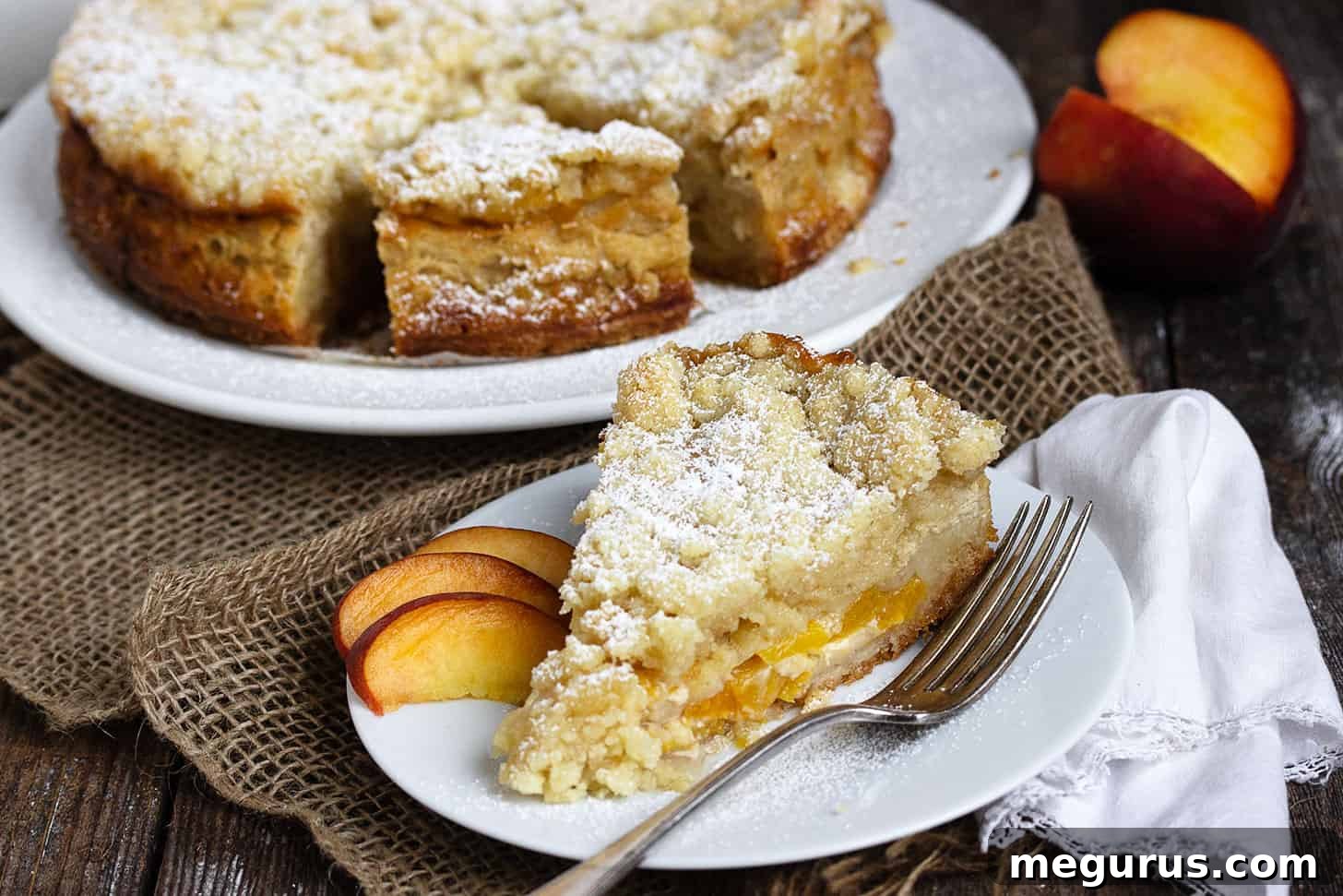 A slice of delicious peach crumble cake on a white plate, showcasing its layers