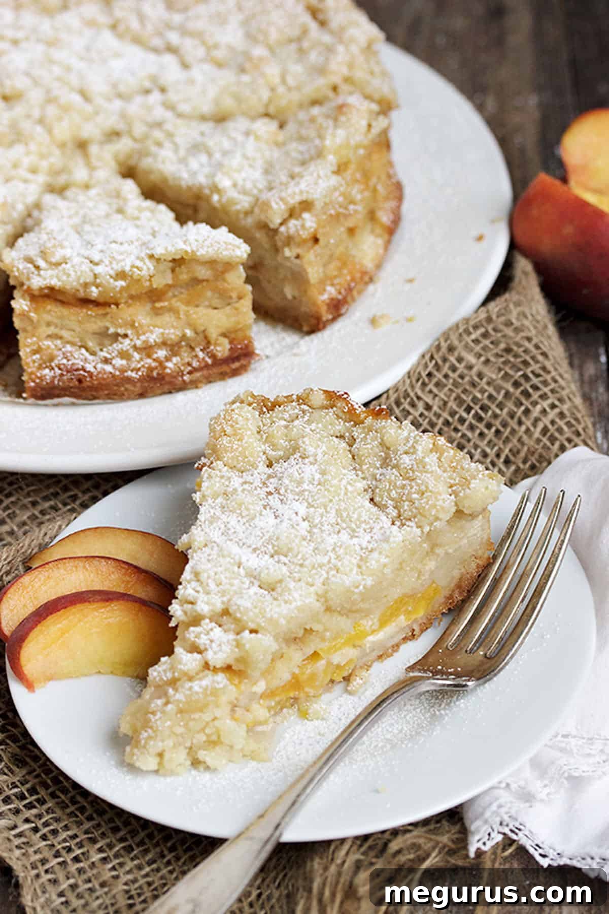 A beautifully sliced peach crumble cake, revealing its distinct layers