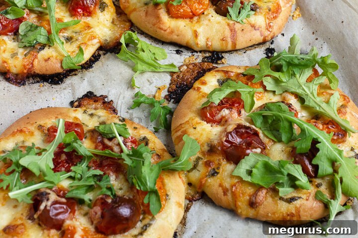mini tomato pizzas on parchment paper