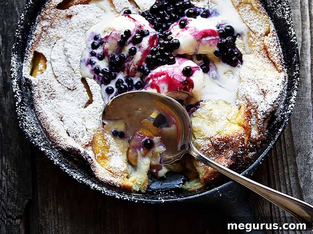 peach Dutch baby with blueberry sauce in cast iron skillet