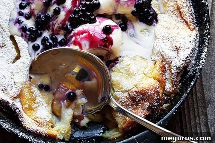 peach Dutch baby with blueberry sauce in cast iron skillet