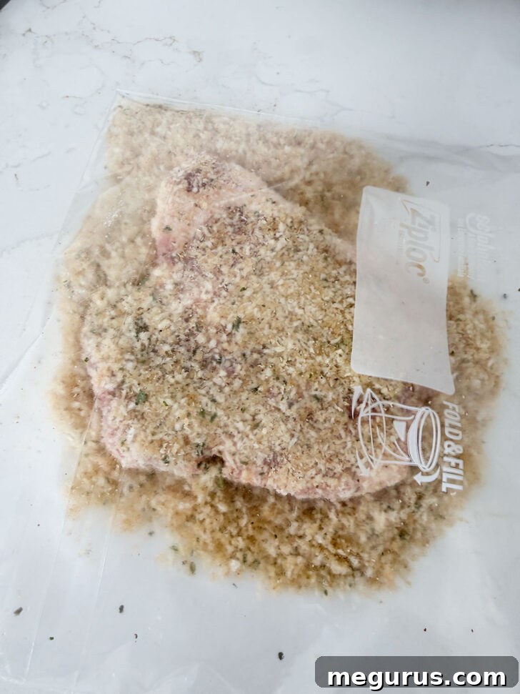 Pork chops being added to the plastic zipper bag containing the panko breading mixture.