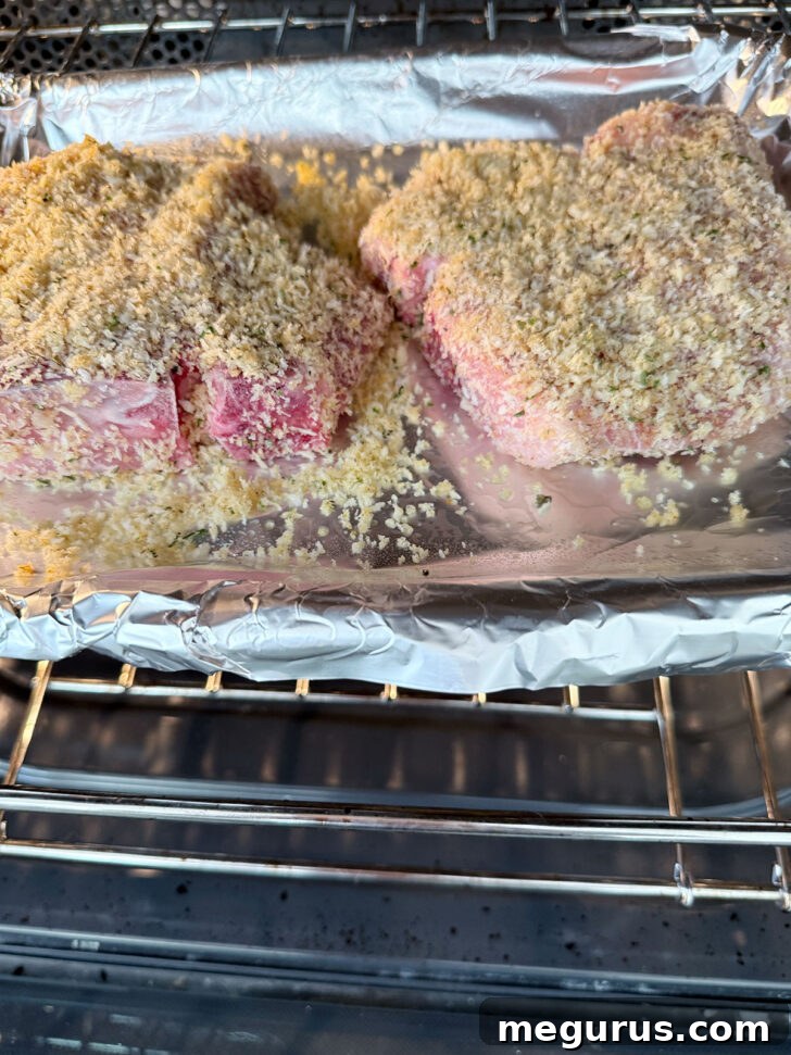 Panko breaded pork chops arranged on a baking sheet and placed into a preheated oven.