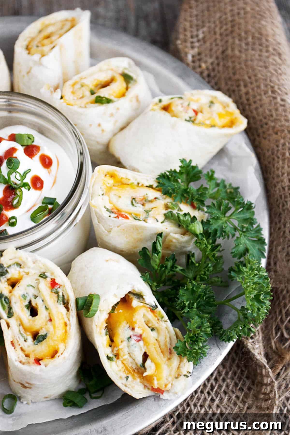 Close-up of baked Antojitos rolls, brushed with butter and sliced halfway through, showing the delicious filling before final cutting.