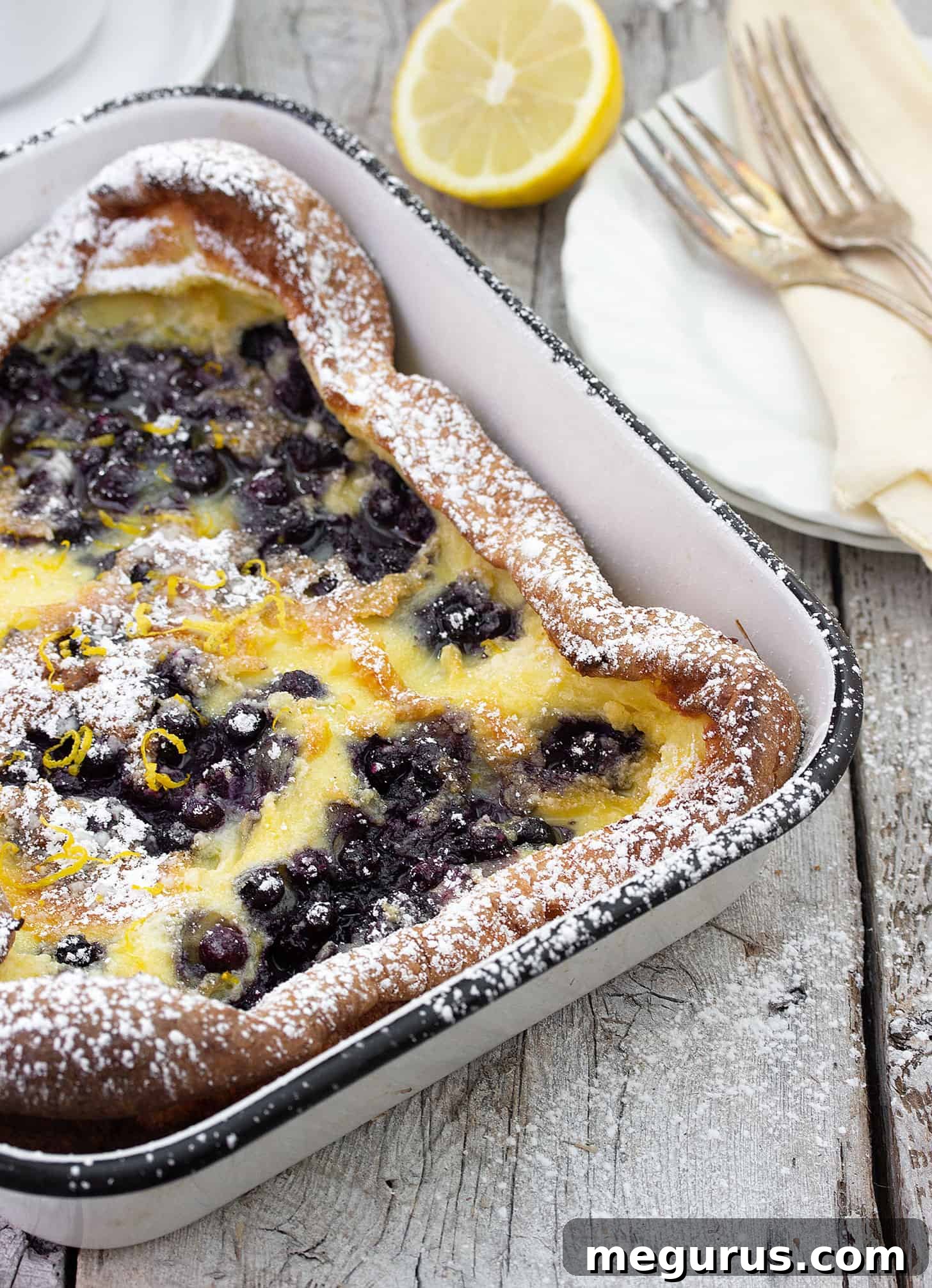 Close-up of baked Finnish Pannukakku in a rectangular dish, showing custardy texture and blueberries