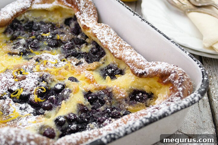 Finnish Pannukakku in baking dish with blueberry sauce
