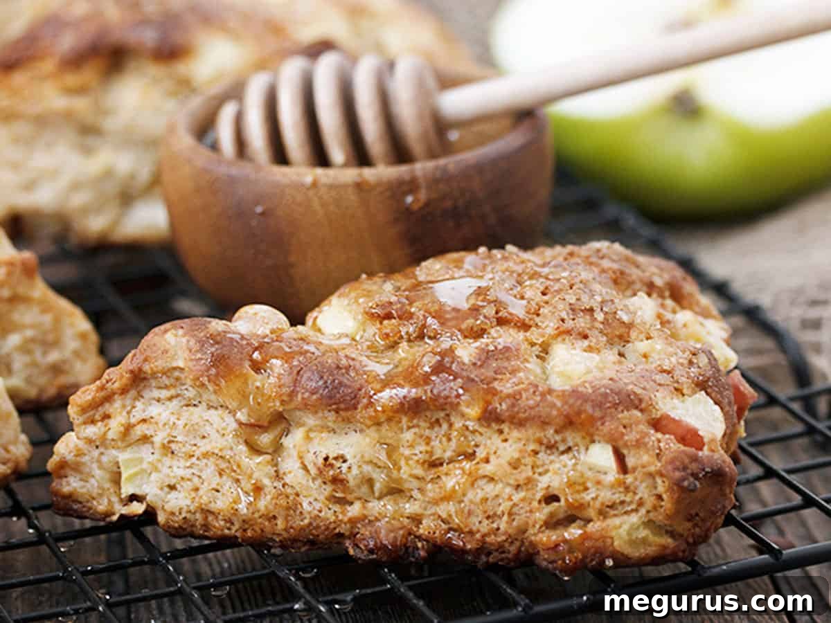 Golden-brown apple buttermilk scones cooling on a rack, freshly baked and ready to be drizzled with honey, highlighting their rustic charm.