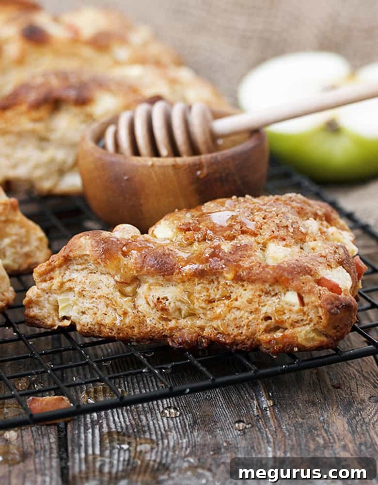Close-up shot of golden honey apple buttermilk scones on a cooling rack, some already adorned with a glistening honey drizzle, emphasizing their delicious appeal.