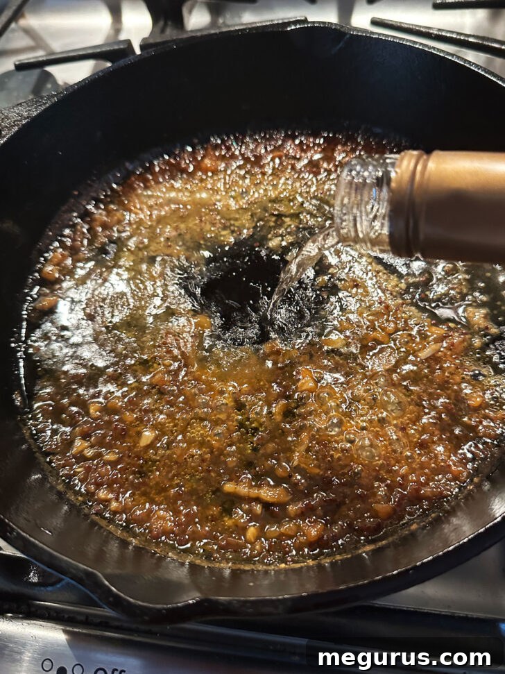 Deglazing the hot skillet with white wine to create the flavorful pan sauce