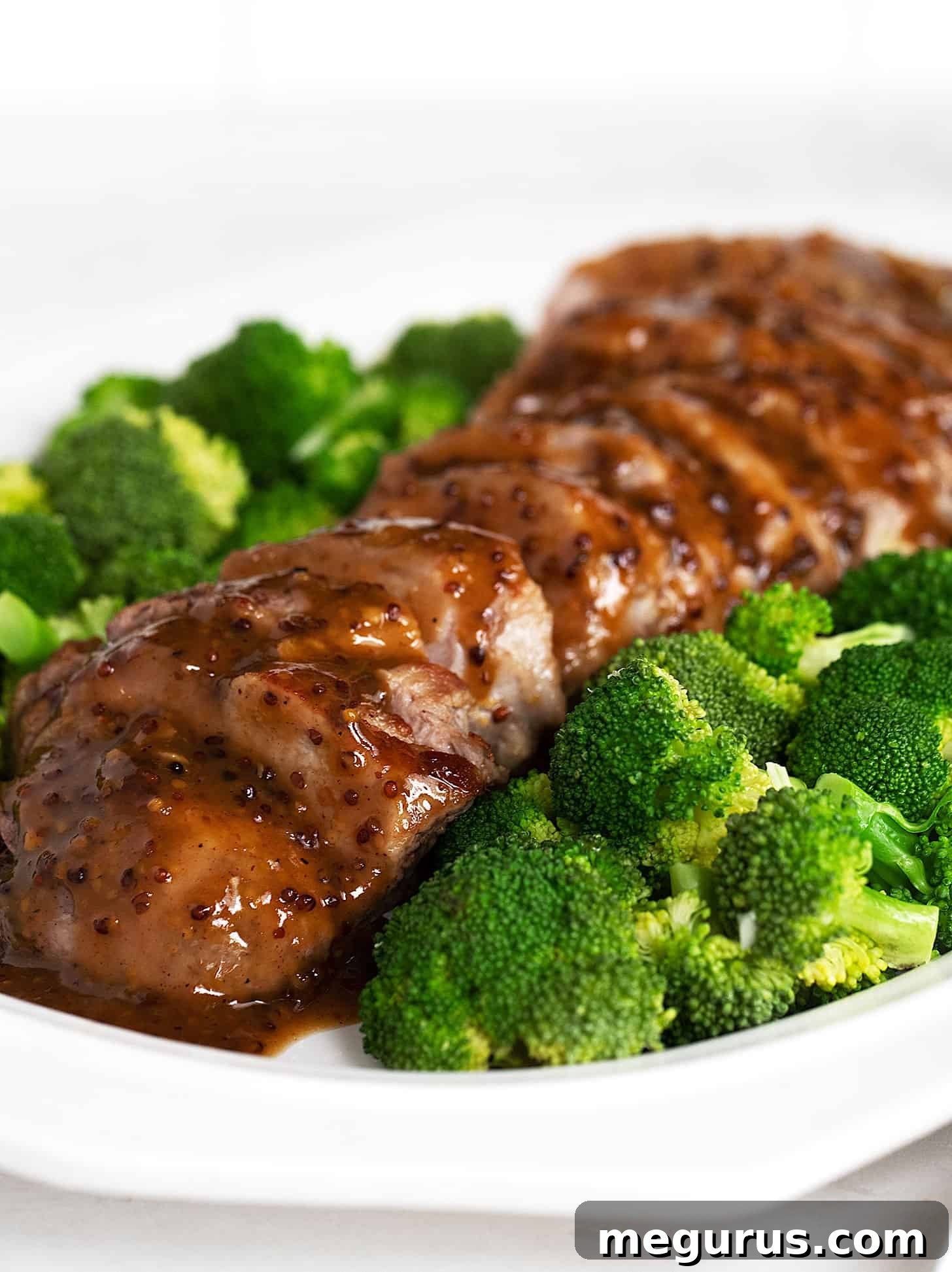 Close-up view of maple mustard pork tenderloin, perfectly sliced and ready to enjoy, highlighting its tender texture and glossy sauce