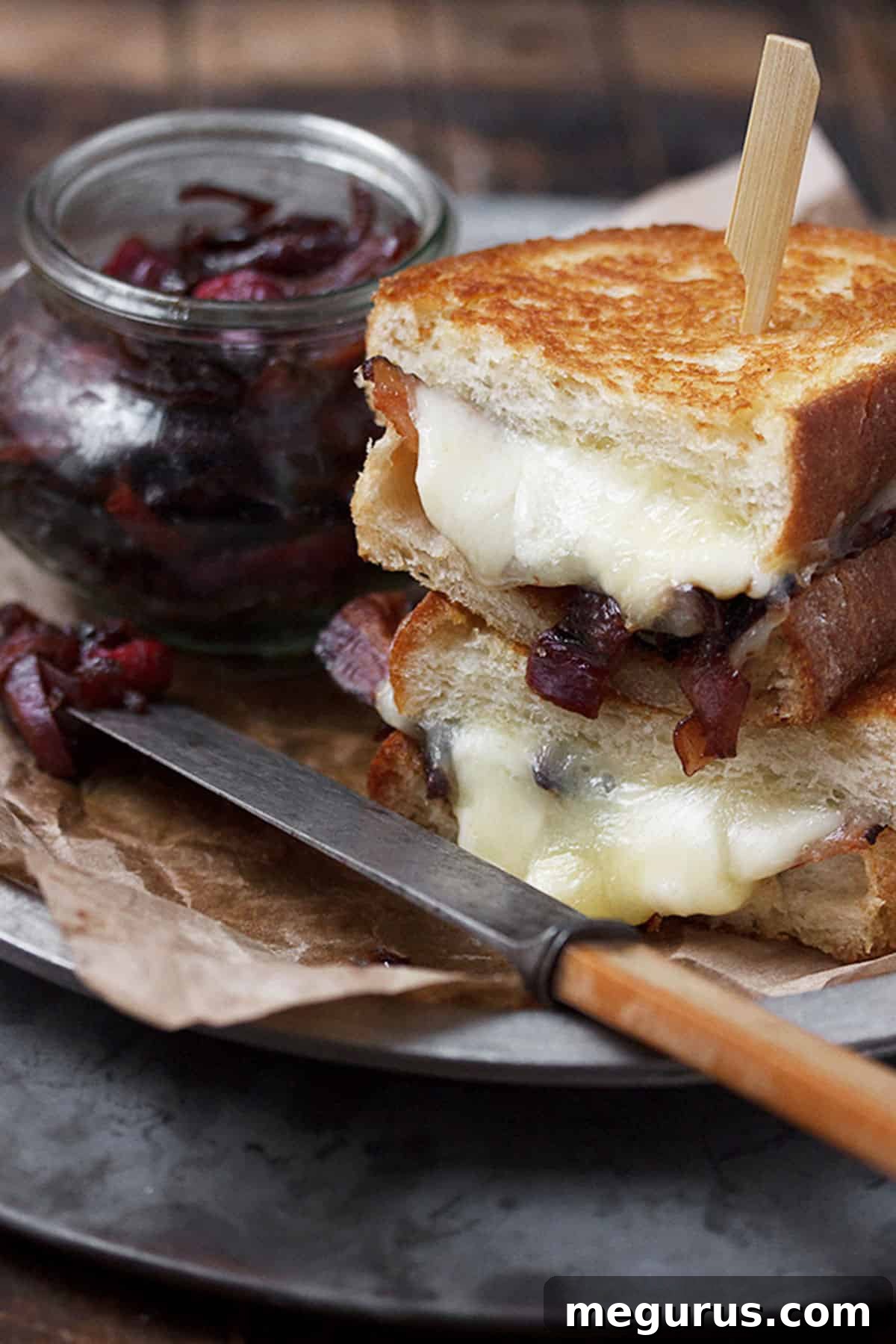 Close-up of a cheese curd grilled cheese, showing the gooey cheese curds and rich bacon onion marmalade.