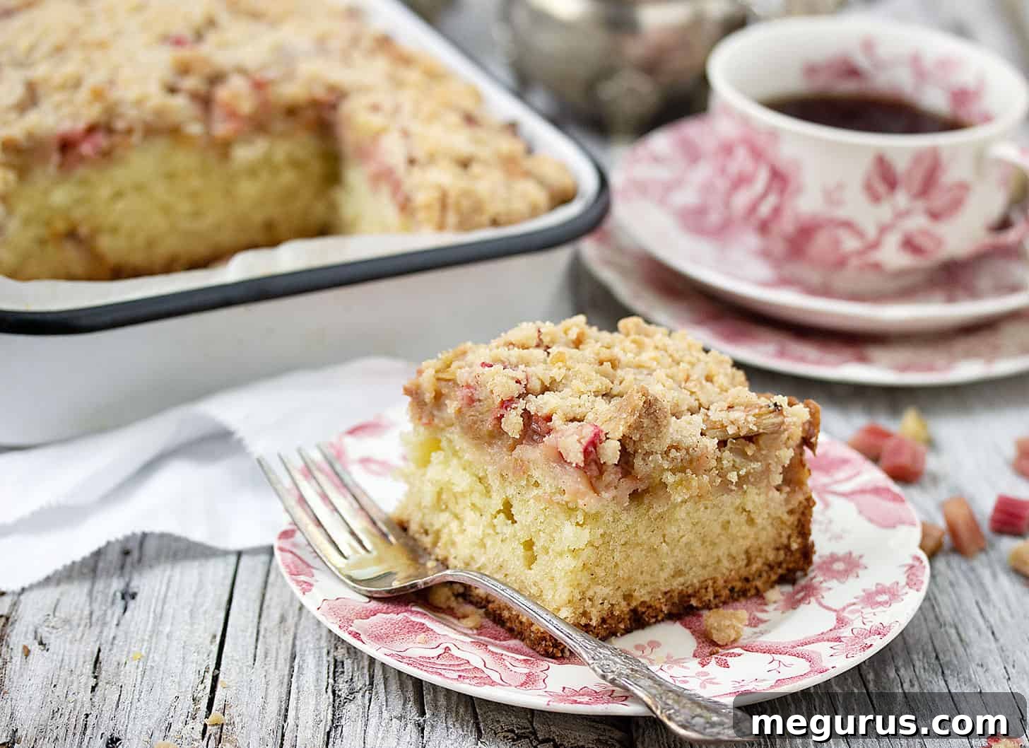 Sliced Rhubarb Coffee Cake on a plate with a cup of coffee