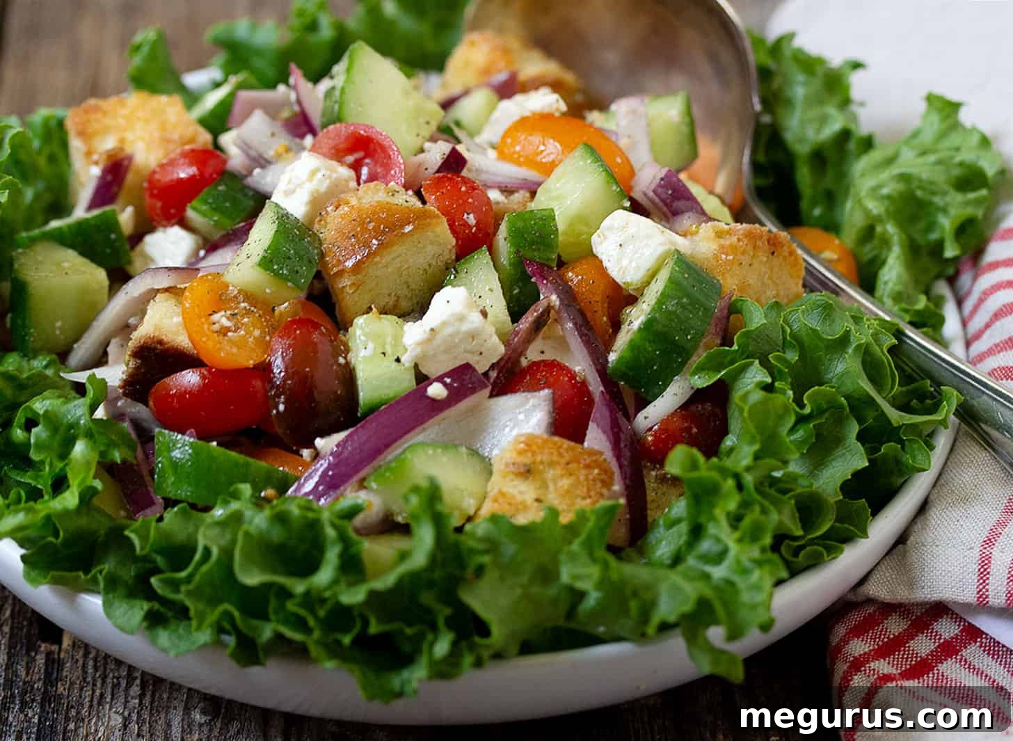 Vibrant Greek Panzanella salad in a rustic bowl, showcasing colorful tomatoes, cucumber, feta, and golden croutons, garnished with fresh herbs.