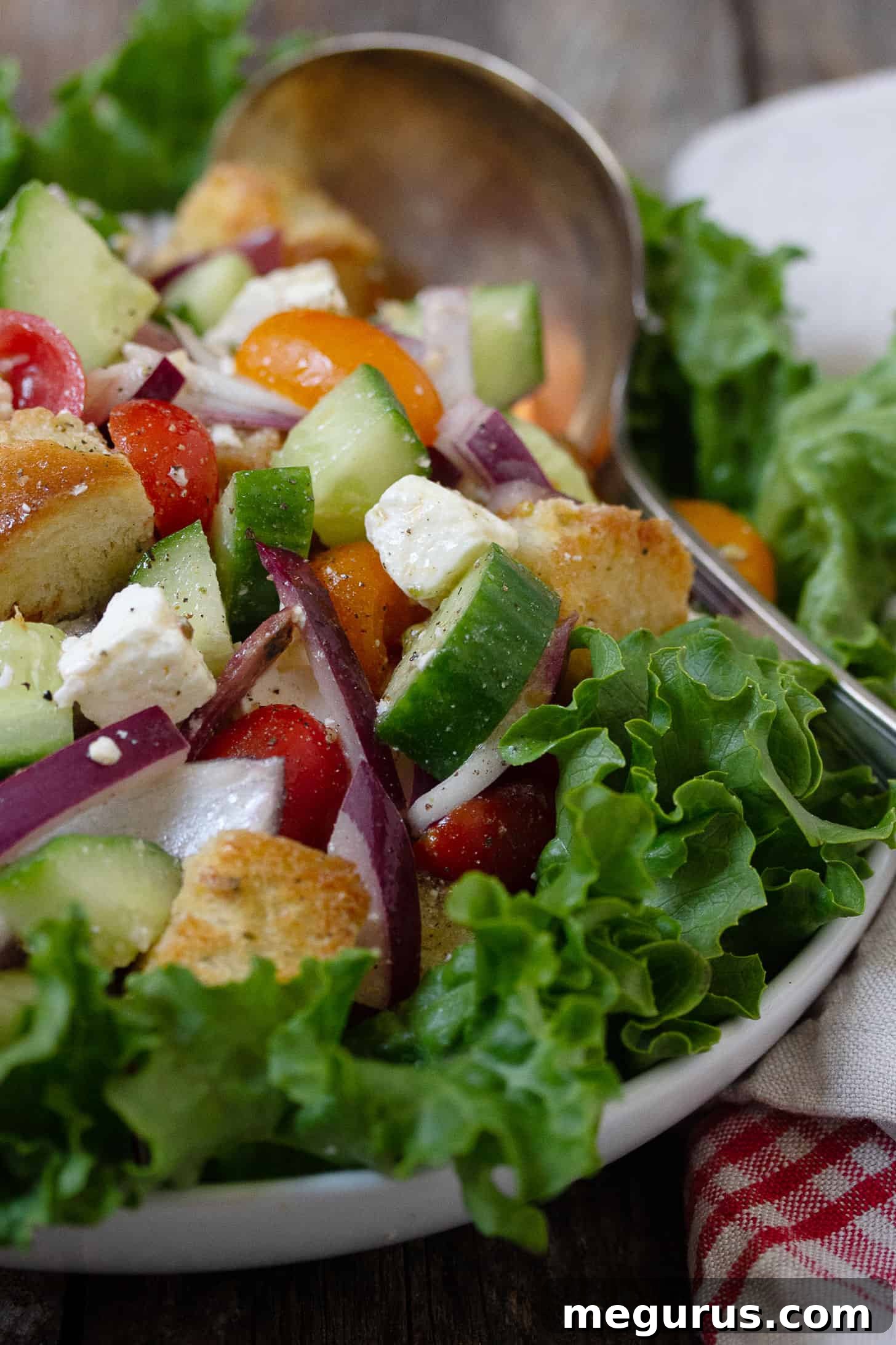 Close-up of Greek Panzanella salad, highlighting the textures of feta, fresh cucumber, and bright red tomatoes amidst homemade croutons.