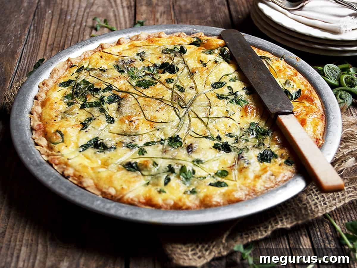 A golden-brown fiddlehead quiche in a pie plate, with a serving knife ready for a slice.
