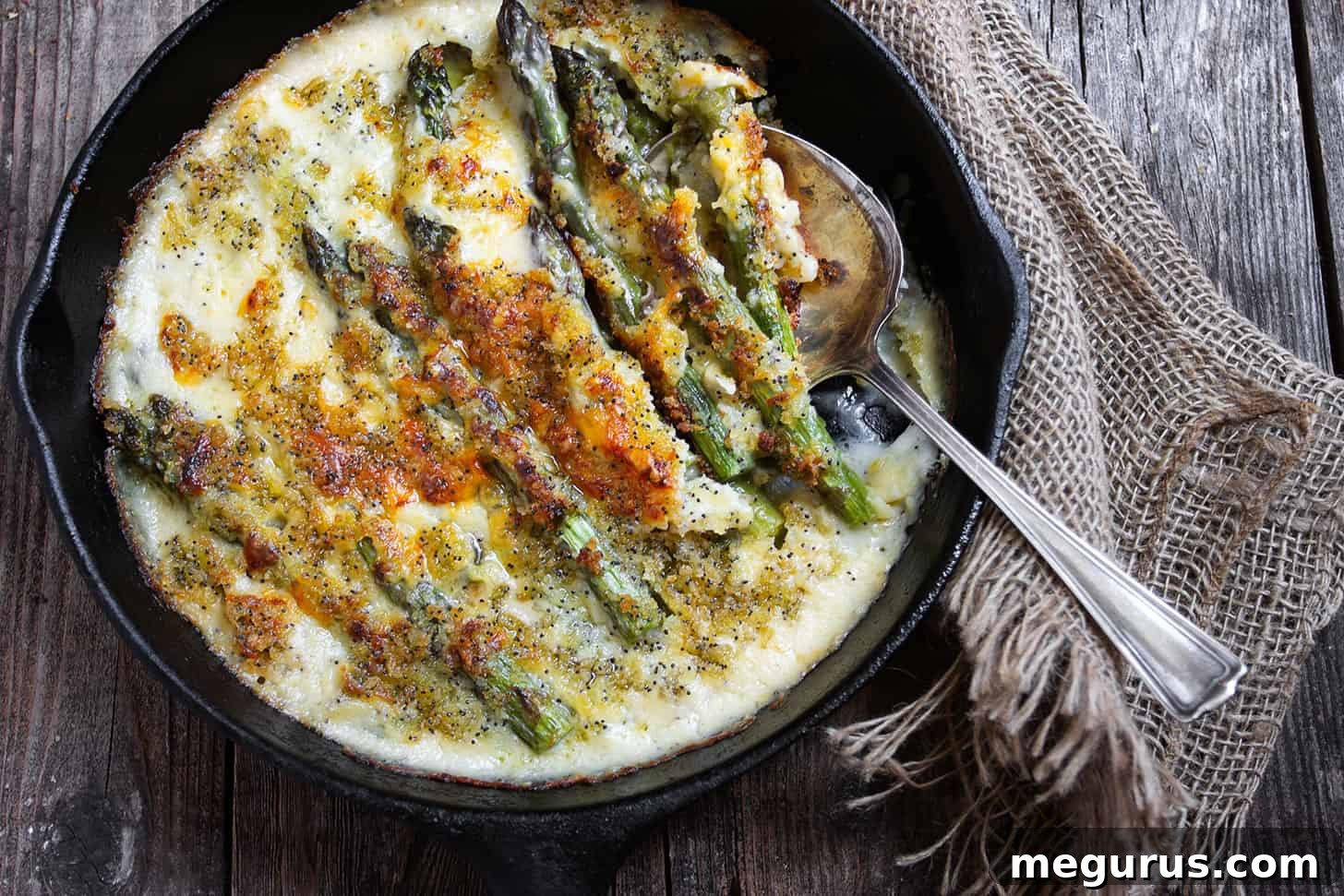 baked asparagus with rich creamy cheese sauce in a rustic cast iron skillet