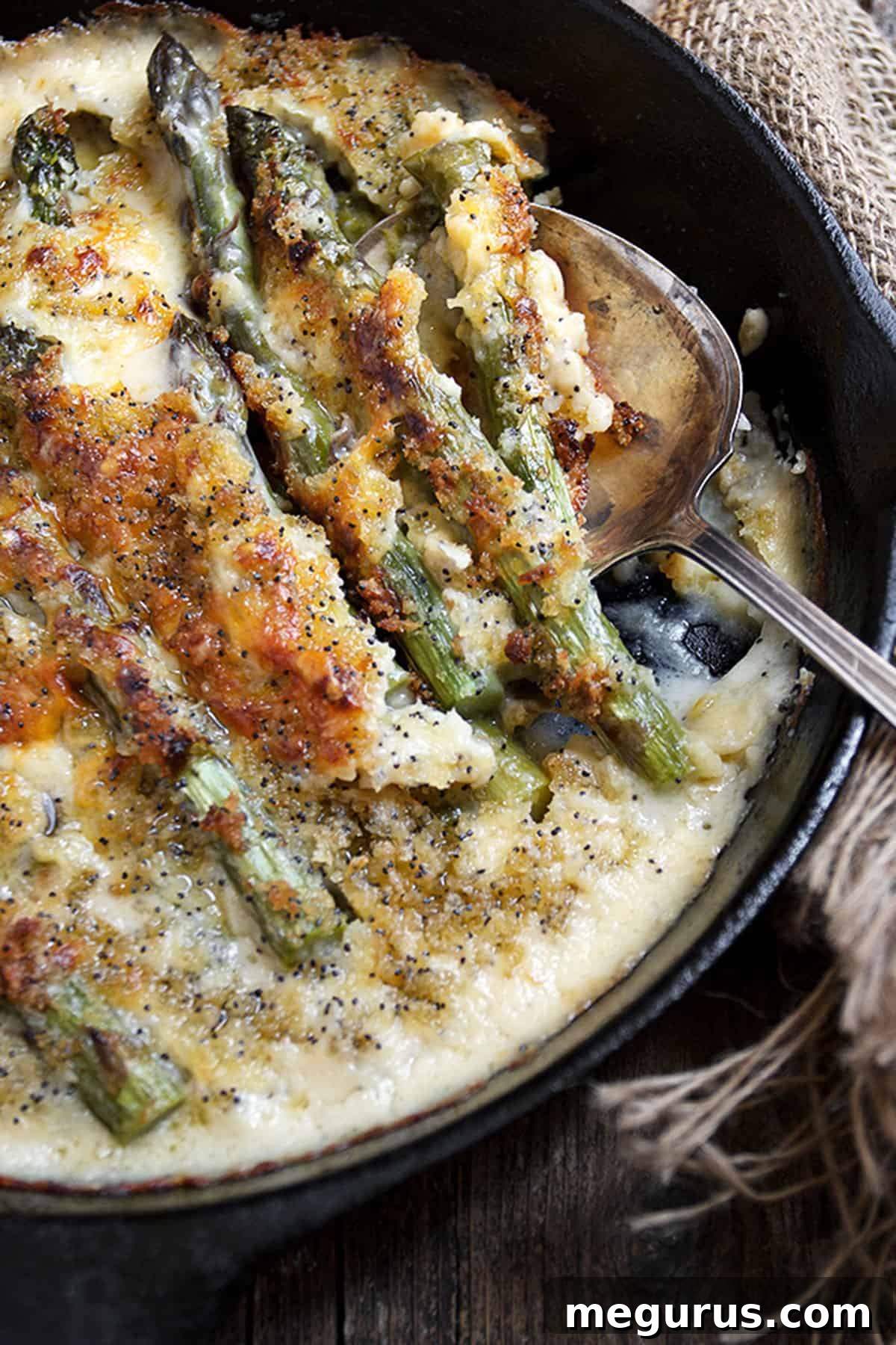 close-up of baked asparagus with melted cheese sauce and crispy panko in a skillet