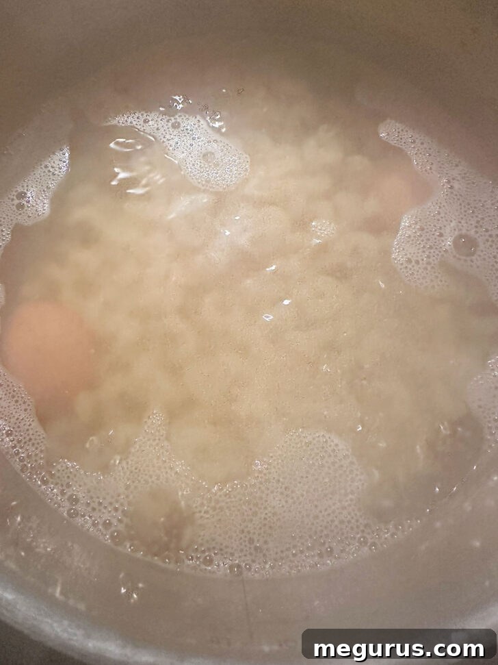 Eggs and pasta boiling together in a large pot of water.