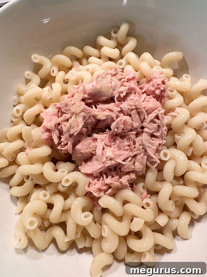 Drained pasta and flaked tuna in a large mixing bowl, ready for other ingredients.