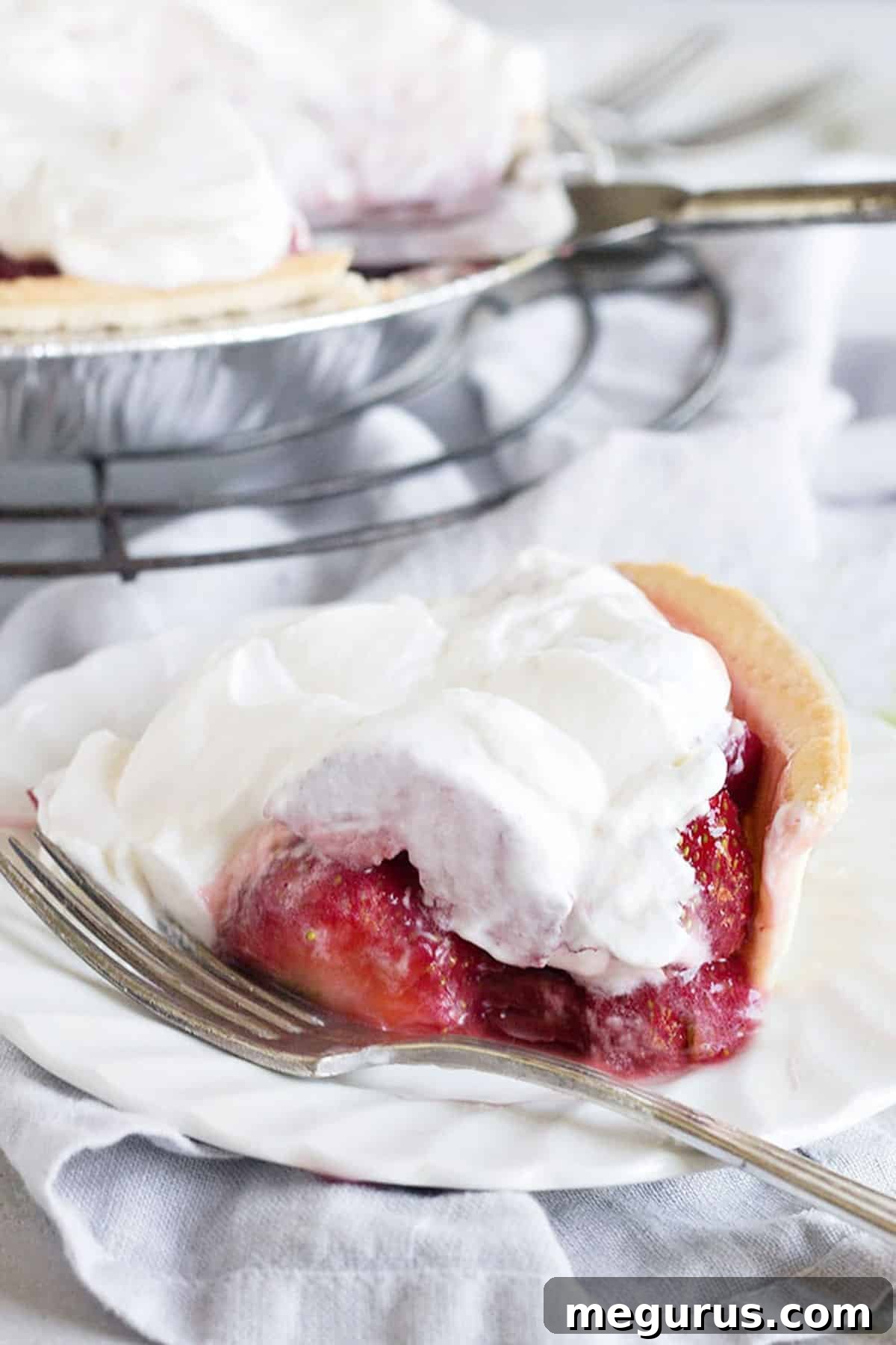 Close-up of Fresh Strawberry Glaze Pie slices on a plate with whipped cream