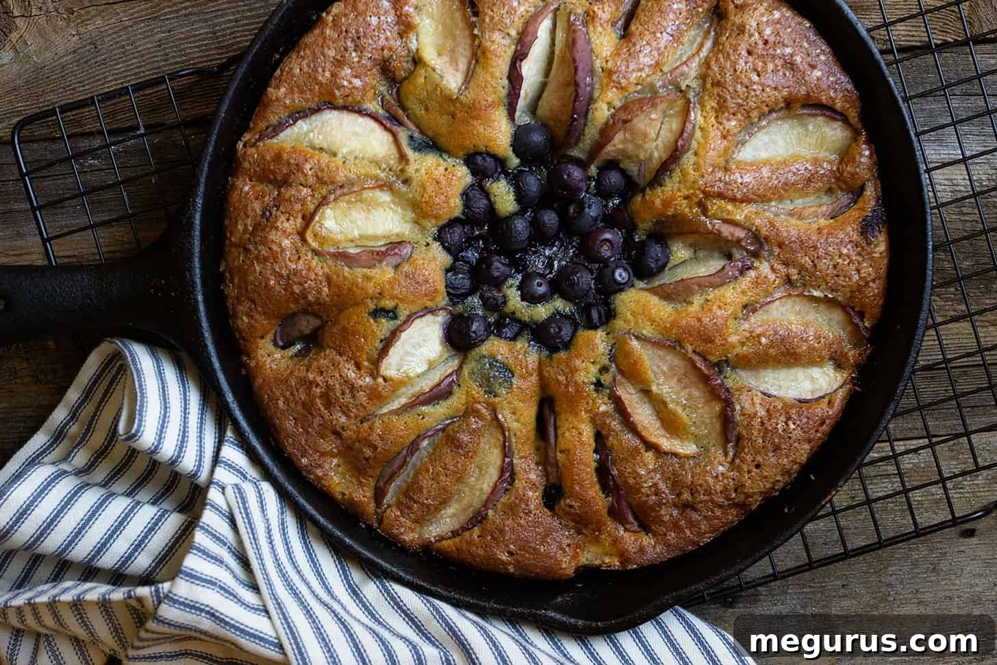 close-up of a rustic blueberry peach skillet cake baked in a cast iron pan, showing golden crust and visible fruit