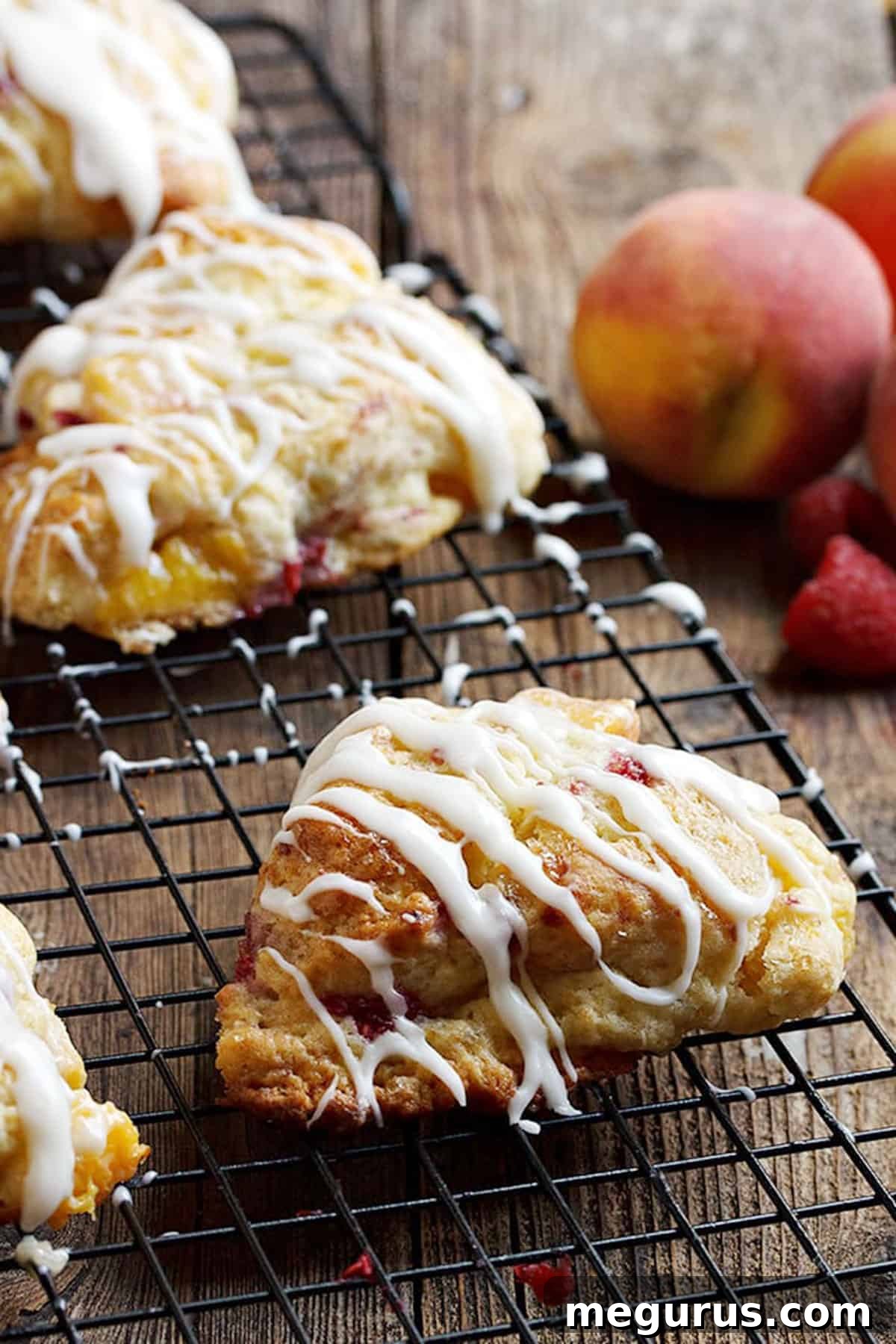 Close-up of golden-brown peach and raspberry scones on a wire rack.