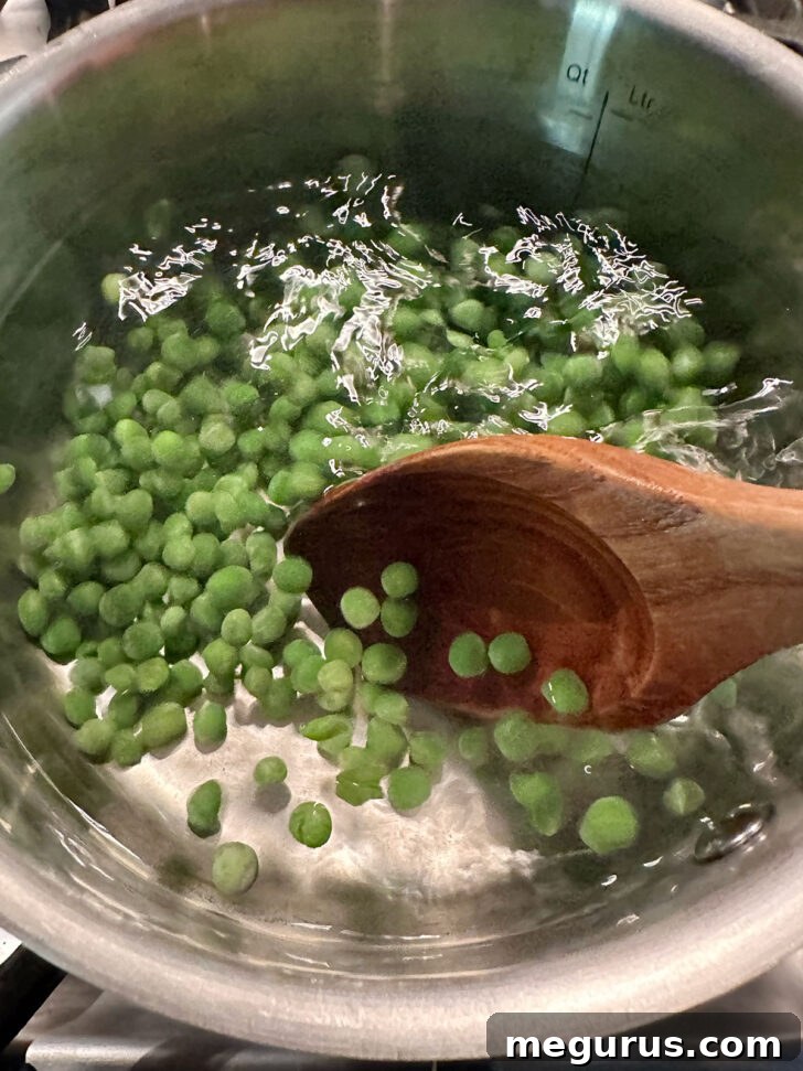 Peas cooking in boiling water in saucepan.
