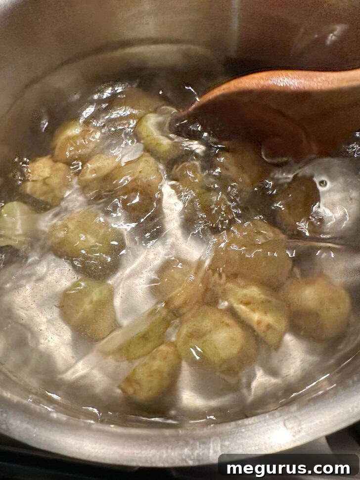 Potatoes cooking in boiling water in saucepan.