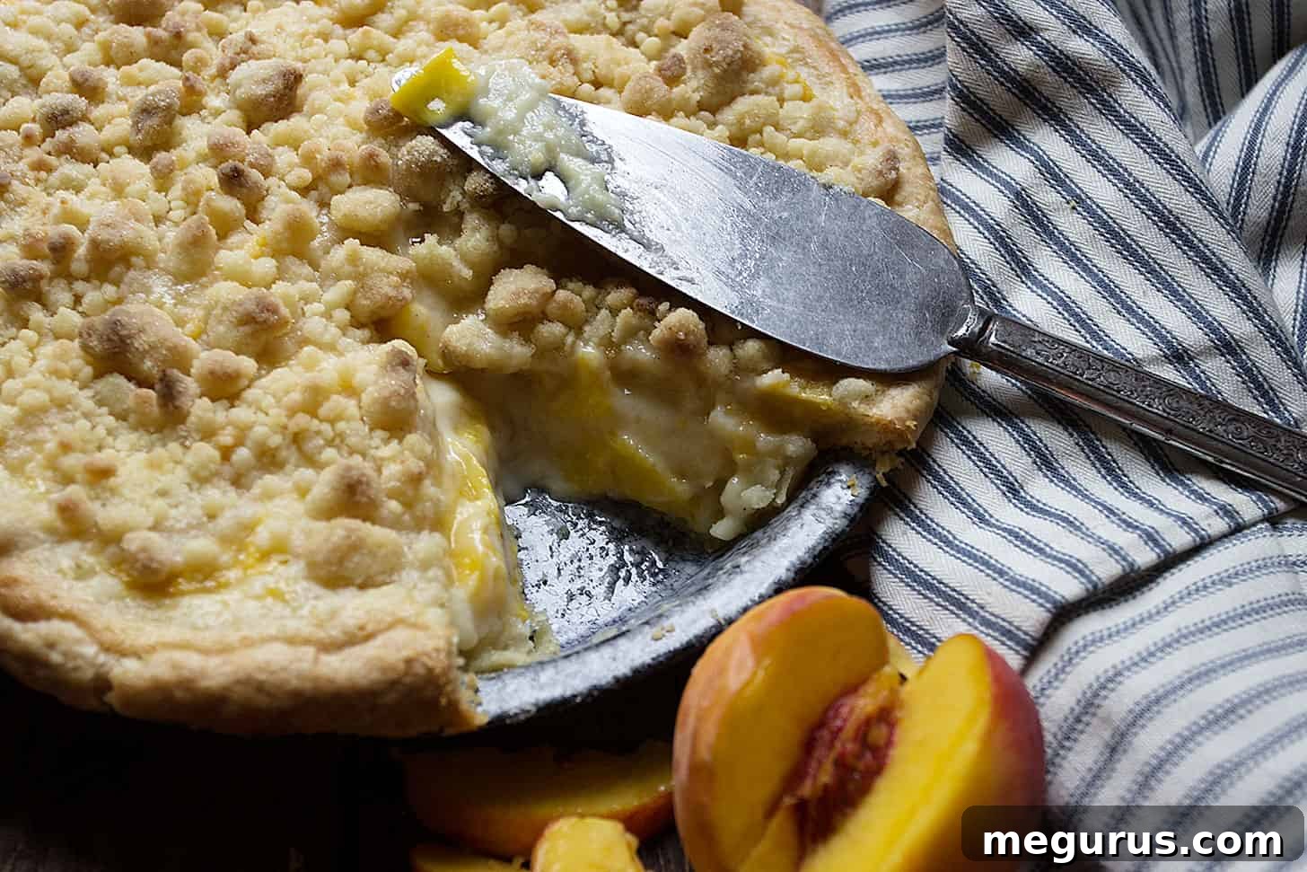 Peaches and Cream Pie with a slice removed, showing creamy filling and crumble topping