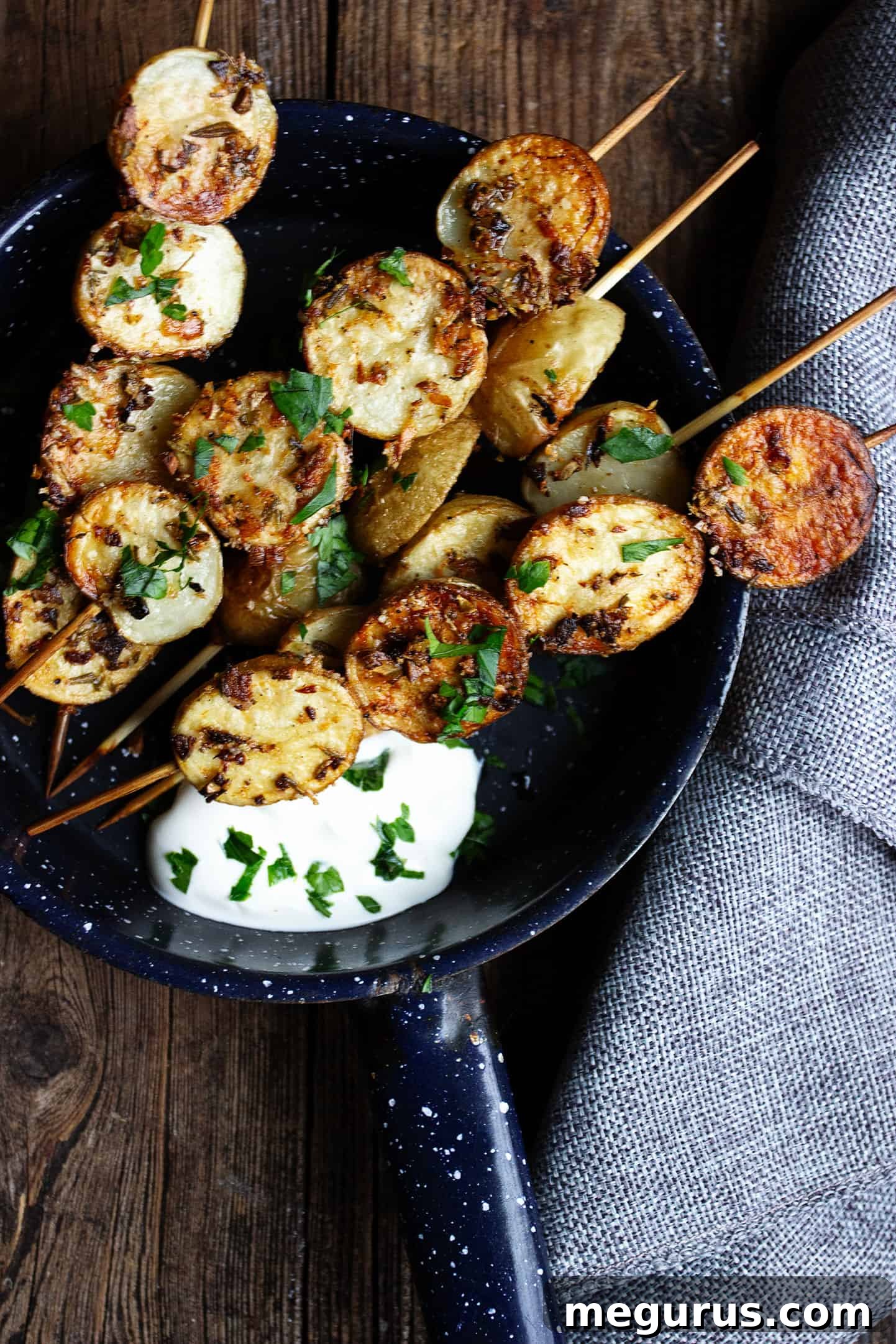 herb and garlic potato skewers in skillet with sour cream