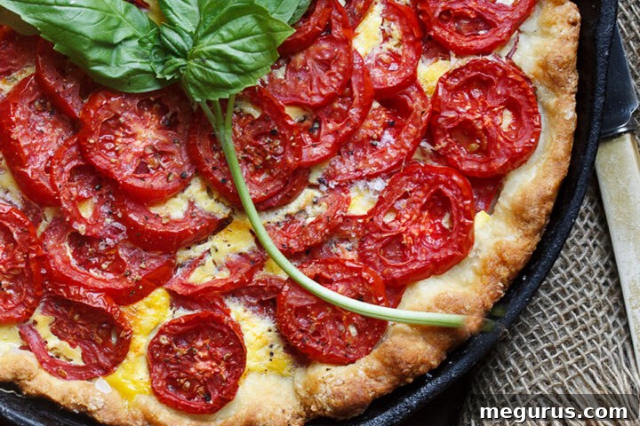 tomato cheese pie is skillet with basil leaves
