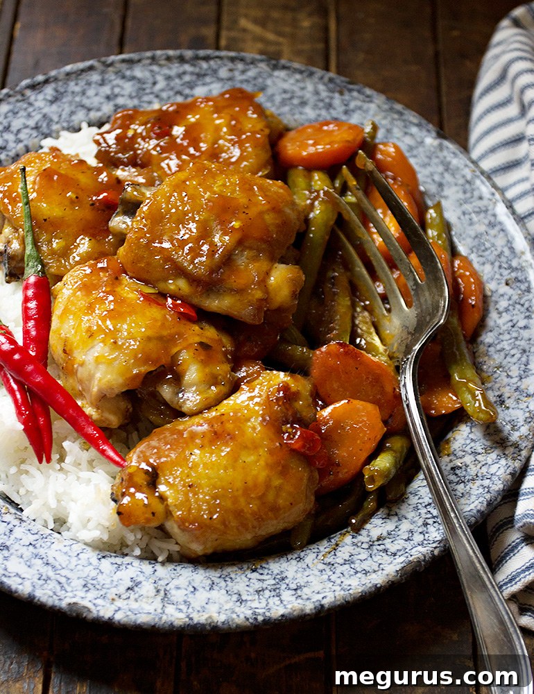 Close-up of Sweet and Sour Chicken Thighs simmering in a skillet with colorful vegetables