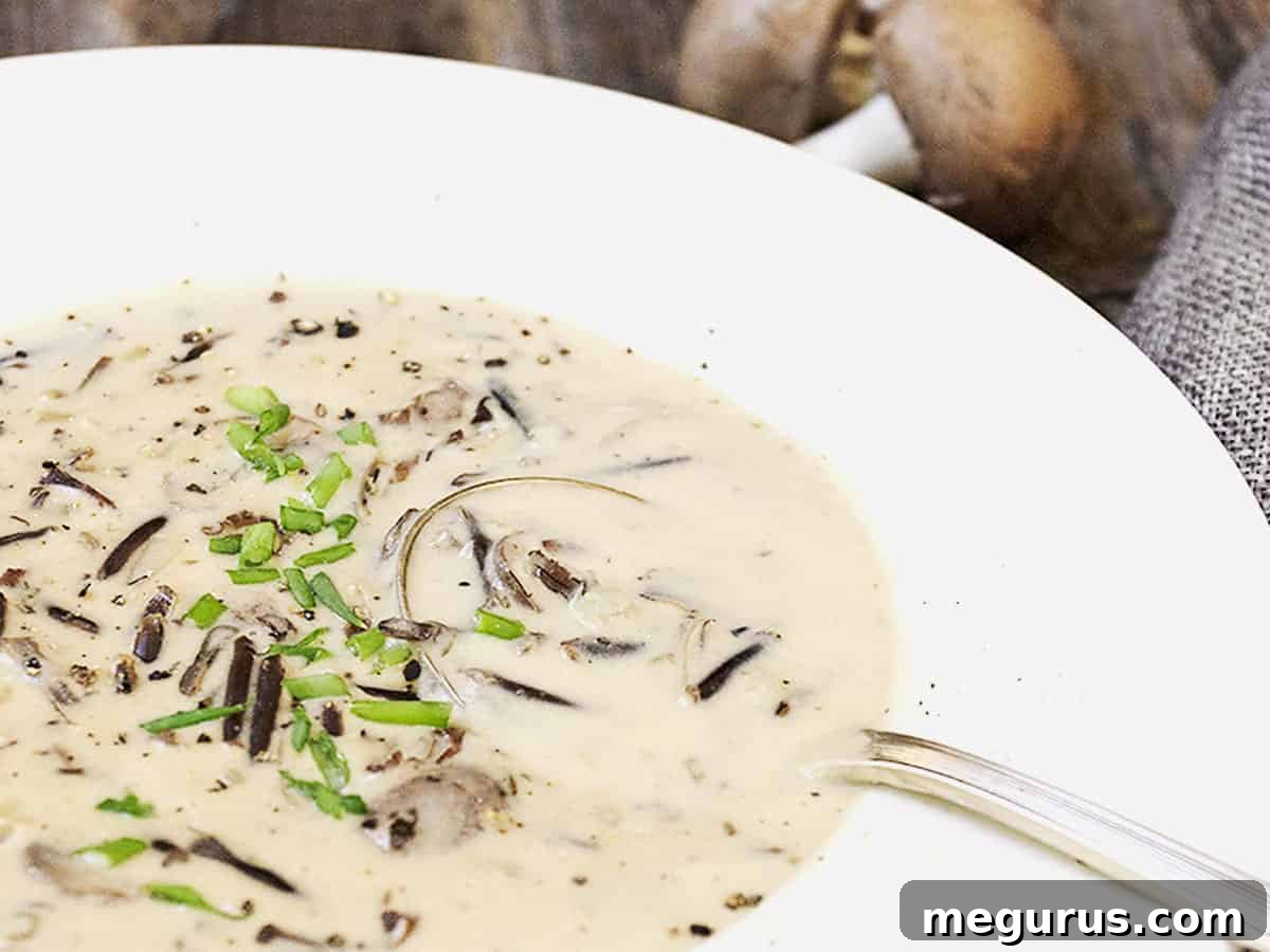 A steaming bowl of creamy wild rice and mushroom soup, garnished with fresh herbs, ready to be enjoyed.